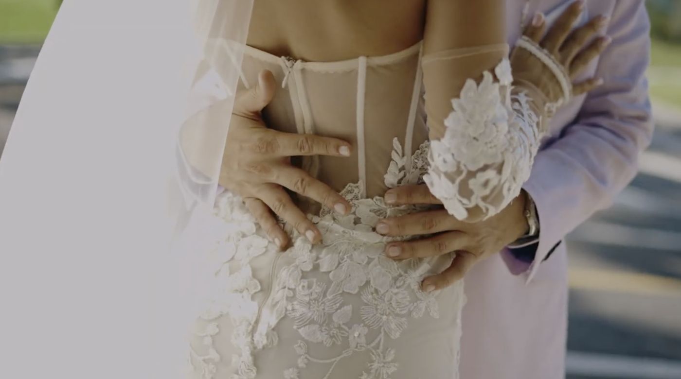 Detalle de las manos del novio sobre el vestido de encaje de Luisa
